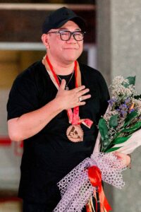 Amir Sali holding flowers after presenting his fashion collection in Dumaguete City
