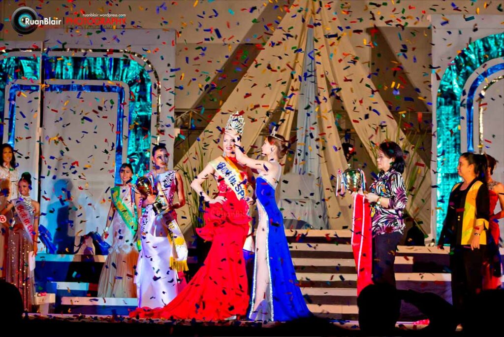 Monica Infante Bartsch being crowned on stage during the Miss Negros Oriental Tourism 2013 coronation ceremony with confetti falling.