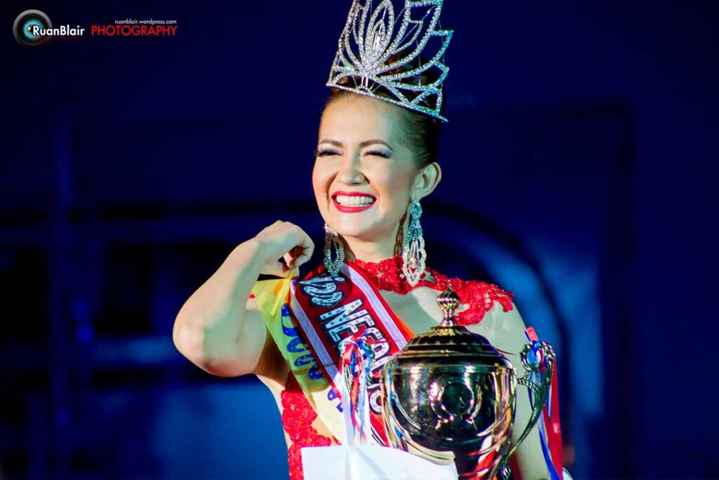 Close-up of Monica Infante Bartsch smiling with her Miss Negros Oriental Tourism crown, sash, and championship trophy