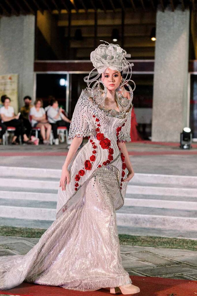 Model wearing a silver embellished gown with red floral details from Amir Sali’s collection
