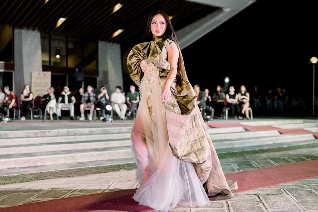 Model wearing an asymmetrical terno by Josip Tumapa with a single sculpted butterfly sleeve